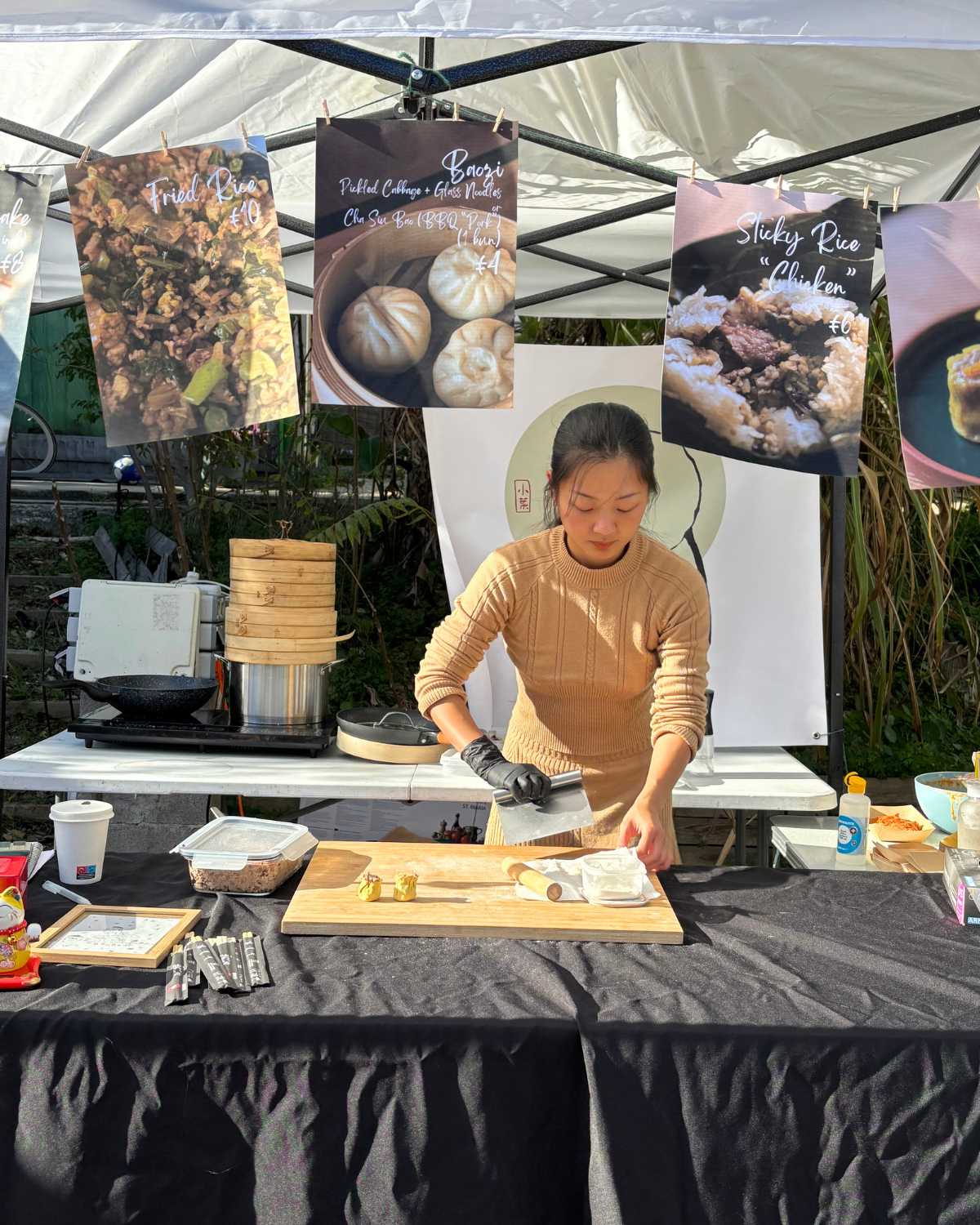 Preparing siu mai dumplings by hand at a Tiny Leaf vegan food stall during an outdoor market.