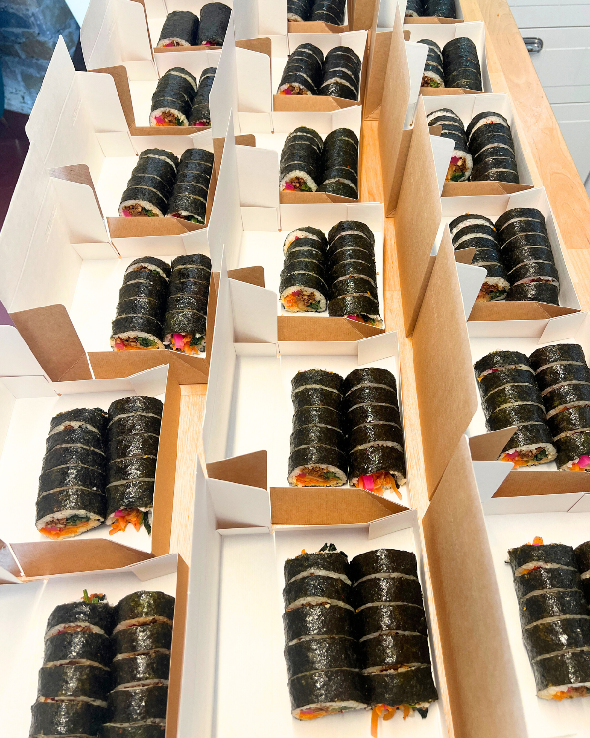 Boxes of freshly made vegan gimbap arranged on a table for delivery in Portugal.