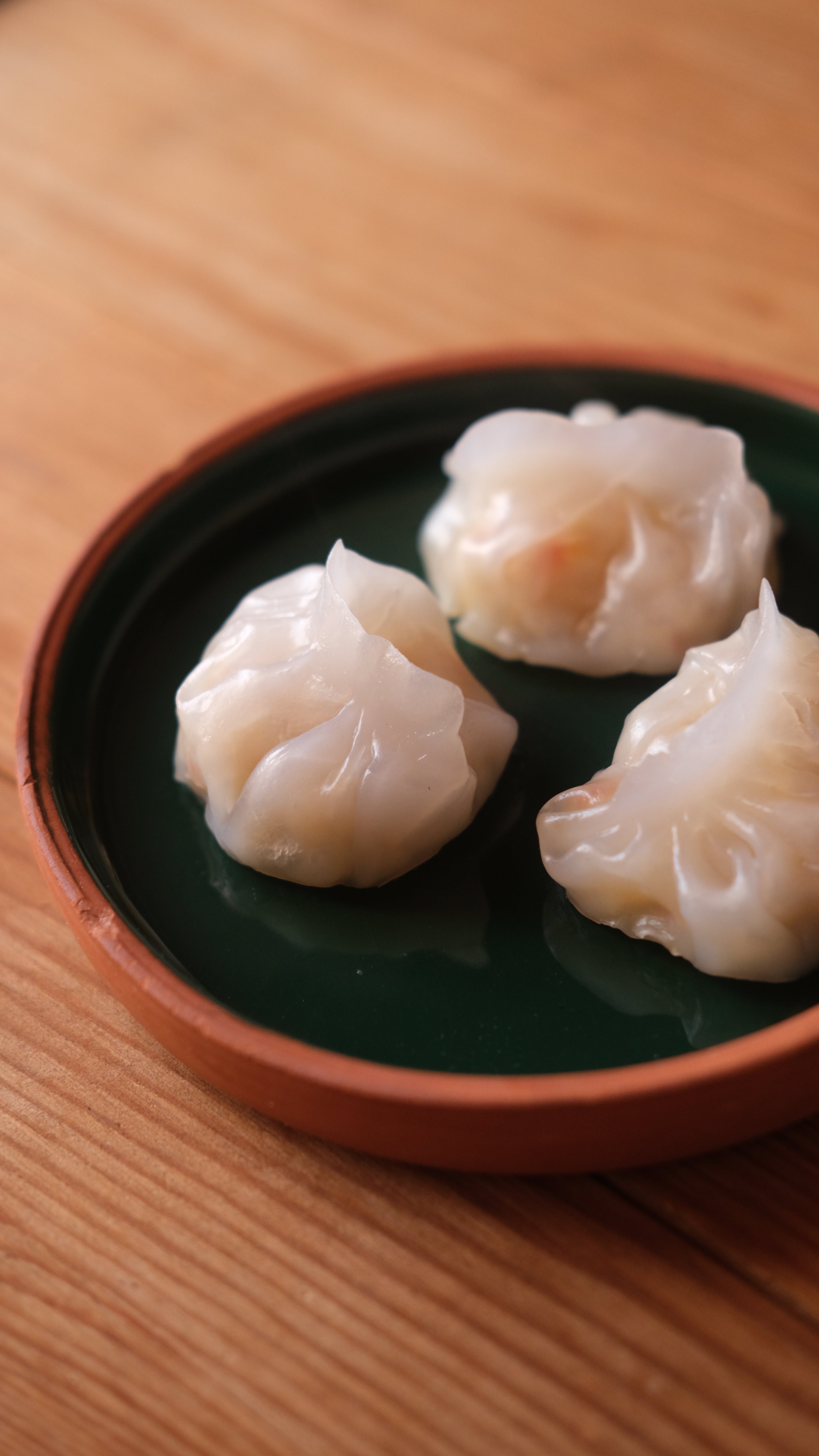 Three vegan har gow dumplings (虾饺) with translucent wrappers served on a small plate.