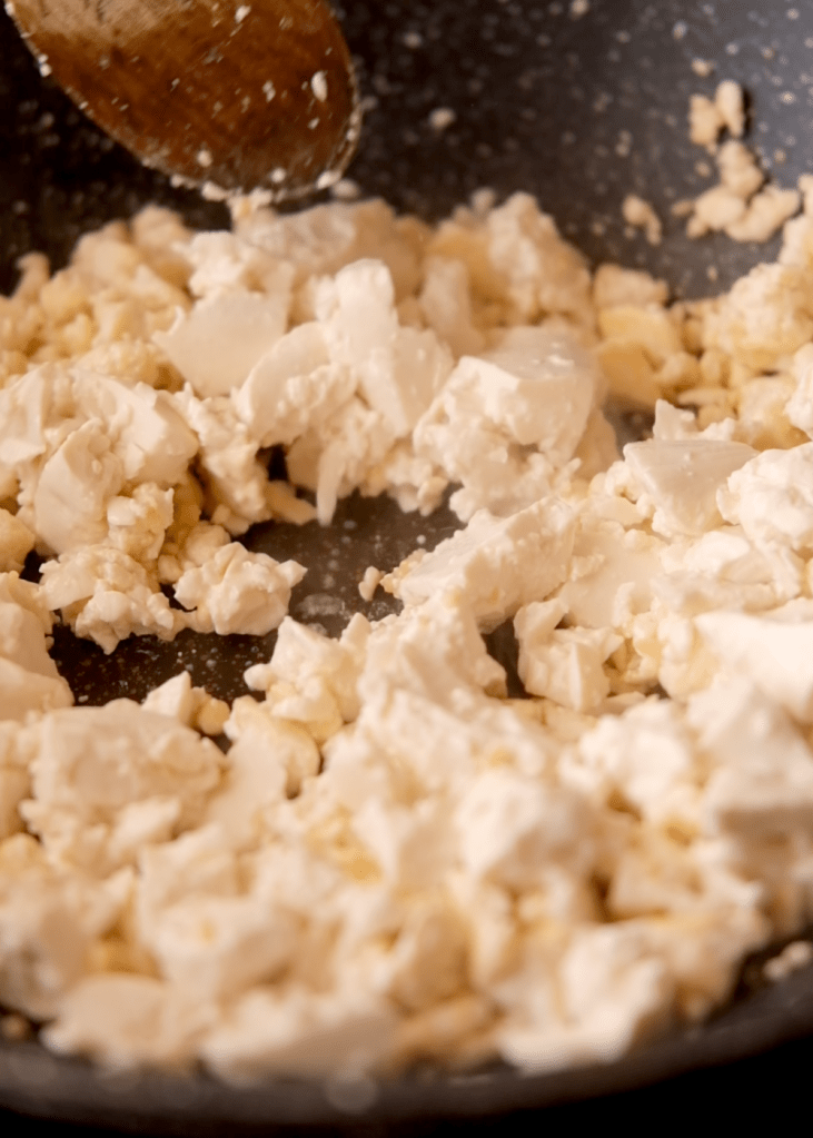 Firm and silken tofu crumbled in a pan as the base for vegan tomato scrambled eggs.